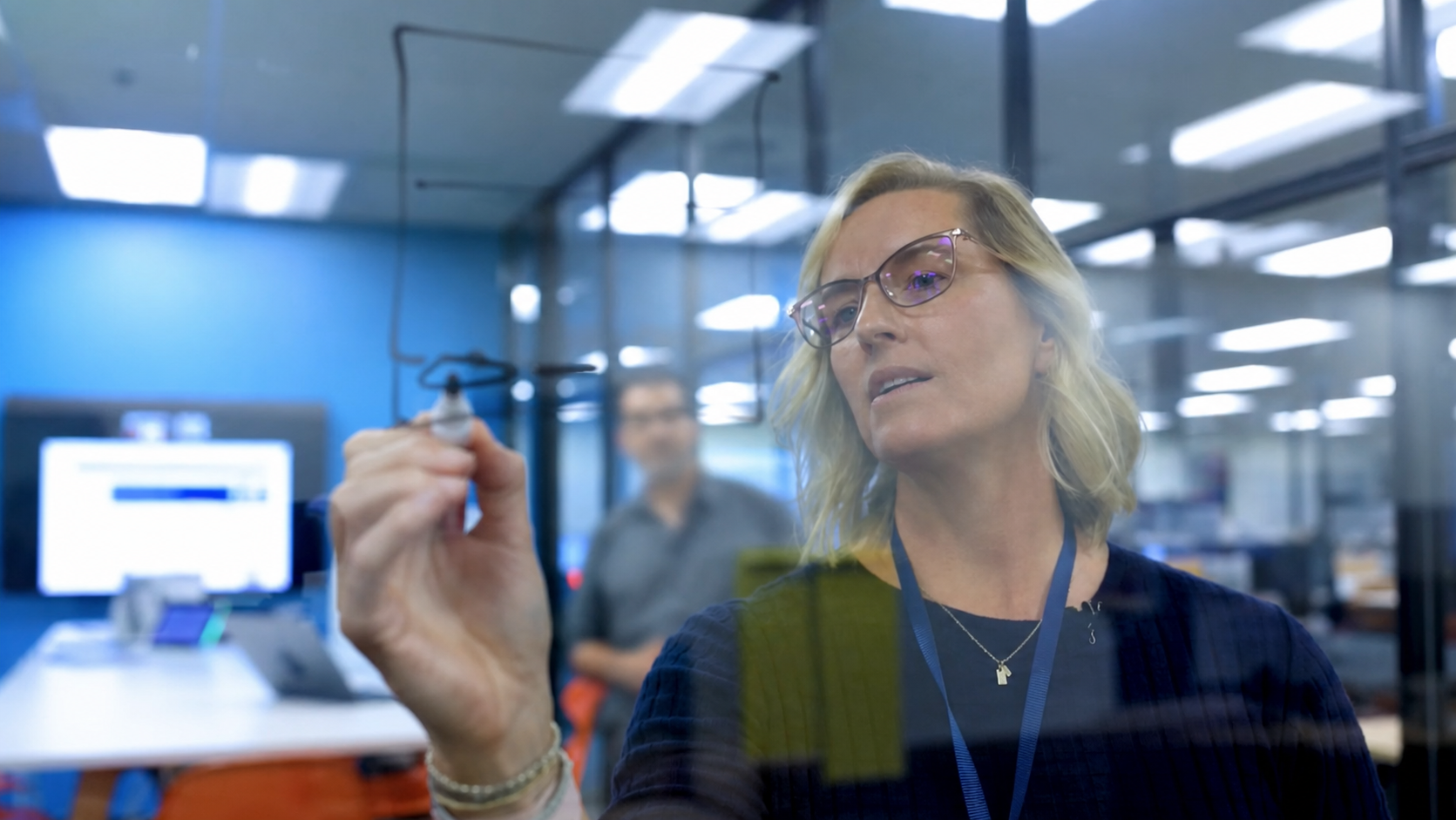 Melissa Waller sketching an experience model on glass in a collaborative workspace.